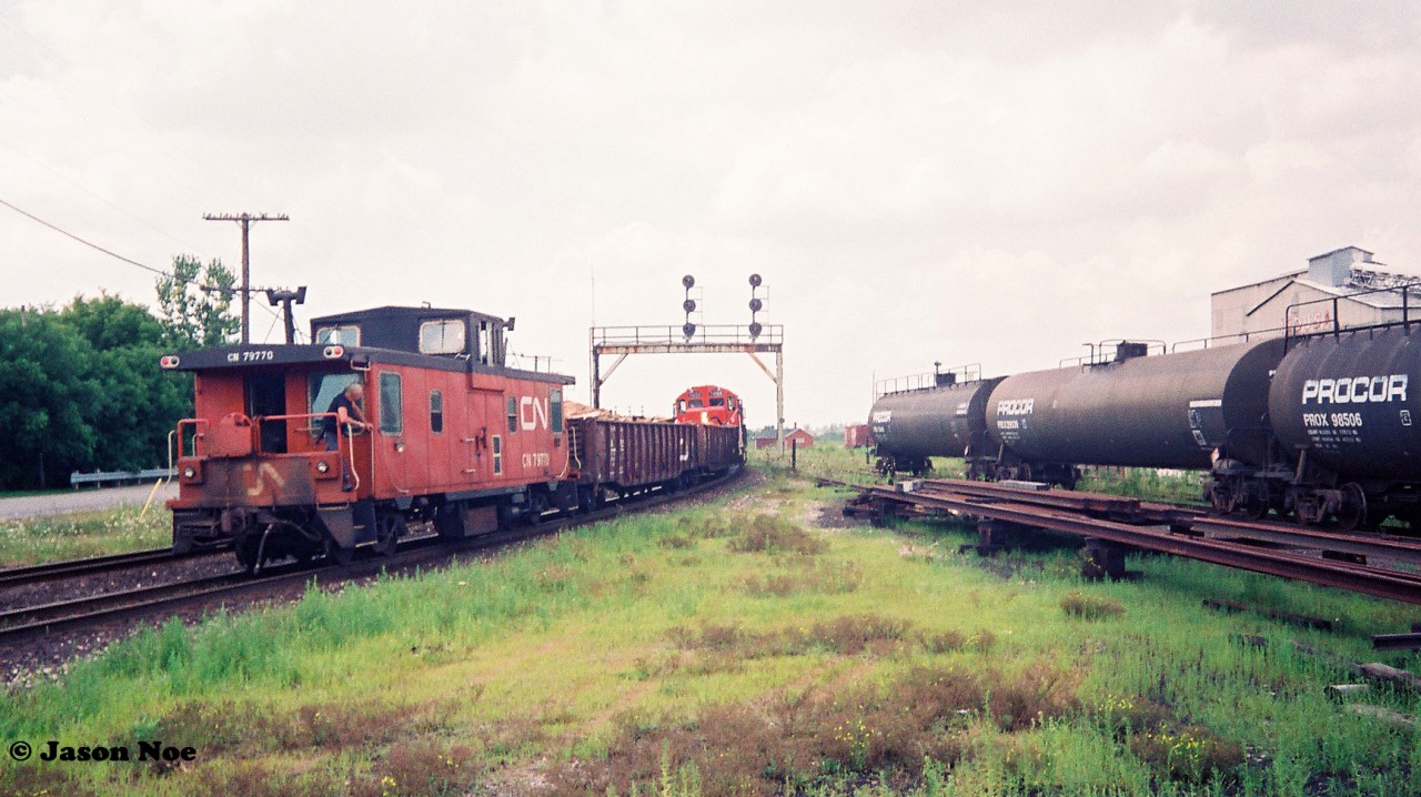 Train 562 is seen curving through Paris, Ontario at it heads toward the pit tracks to set-off loaded gondolas on August 8, 1993. Powering the small train are GP9RM’s 7035 and 7036 with caboose 79770 on the tail-end.