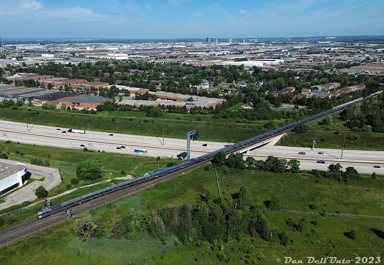 VIA Rail #1 "The Canadian" has just come up from Union Station via the Newmarket Sub, and is beginning its reverse movement onto the CN York Sub for the trip east to Doncaster (and up the Bala Sub). Here, rear dome-observation park car Kootenay Park leads the 21 car consist off the Newmarket Sub, splitting the signals at Snider North as the train crosses back off the Highway 407 ETR overpass. A York Region Transit bus (LFS 1710) can be seen running the Route 760 Vaughan Mills / Wonderland route, originating from the cluster of new condos (around Vaughan Mills) and the faint roller coasters of Canada's Wonderland visible in the distance.

Head end of the same train: http://www.railpictures.ca/?attachment_id=52620