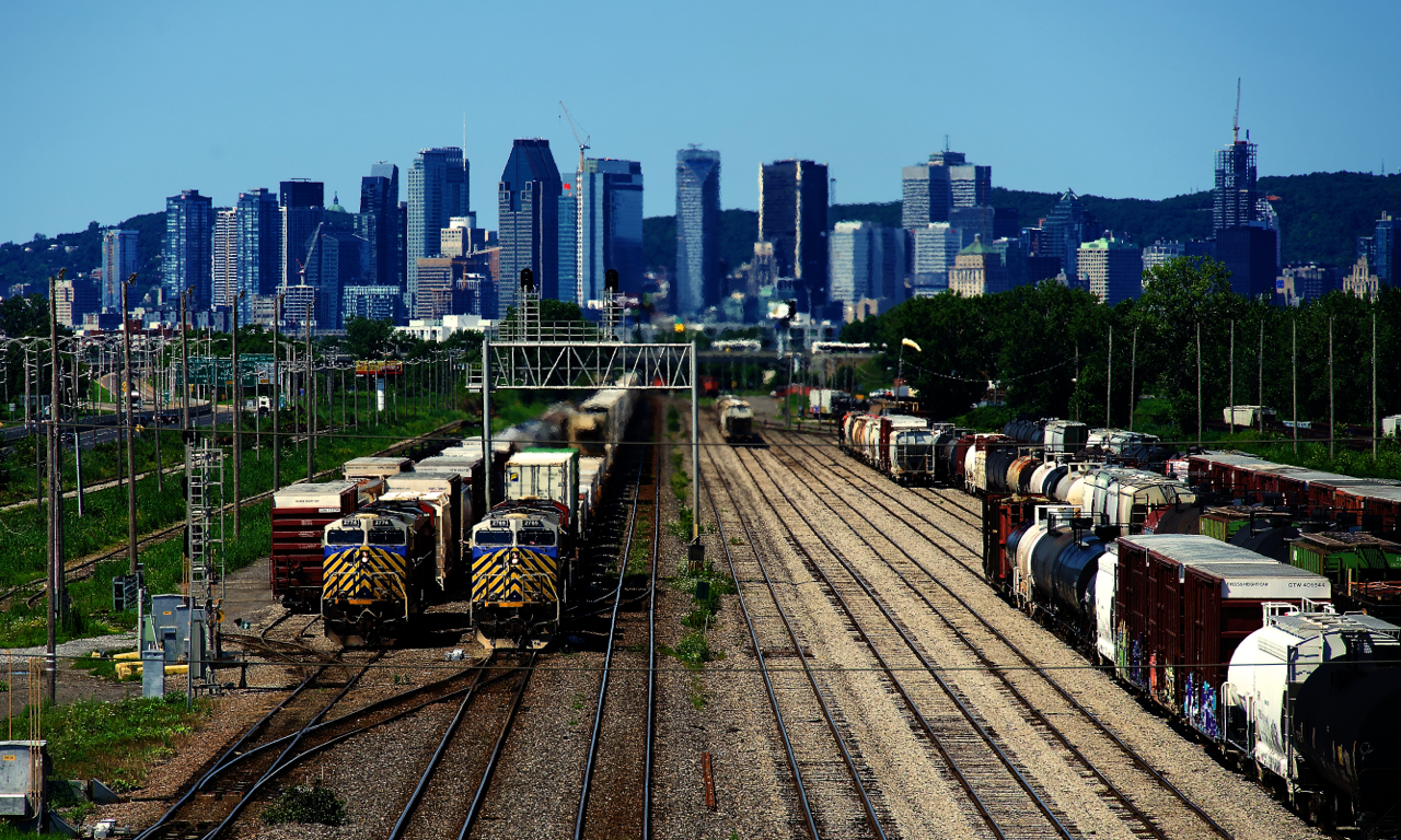 Two units from the second batch of ex-CREX units that CN bought are side by side as CN 120 with CN 2765 leading passes CN 322 with CN 2774 leading. CN 322 has just set off their train on the South Service Track and is waiting for CN 120 to pass before the power heads to the shops.