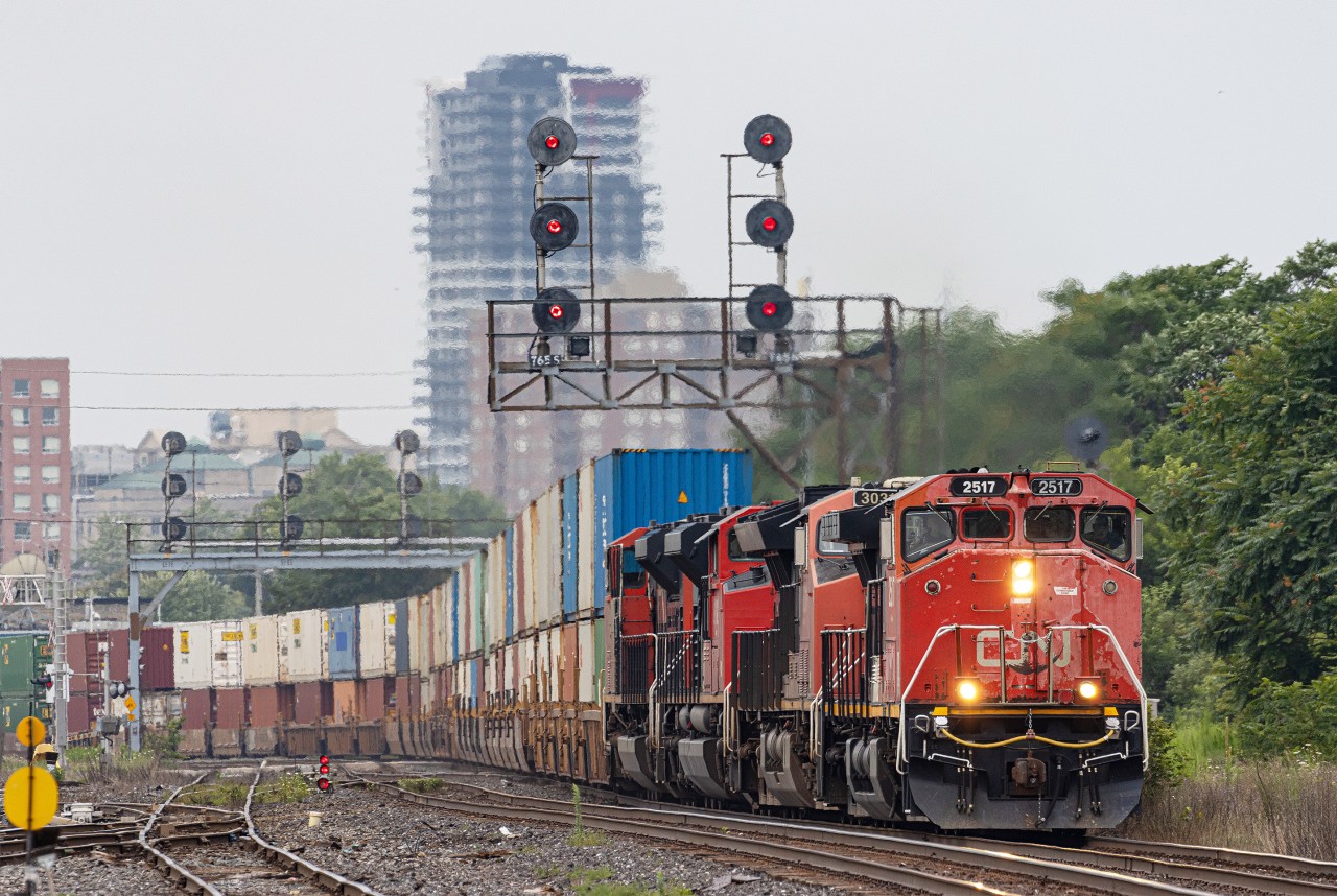 CN 2517, a GE C44-9WL, takes charge of CN 148 as it heads past London Junction on August 6, 2023.  SD70ACe 8102 was the original leader, however it faced PTC issues while the train was stateside.  CN 3031 was added on later, and eventually the 2517 (not PTC equipped) was tacked on in Sarnia.  This was a unique scenario, and seeing a Canadian cab leading 148 is certainly uncommon.  

The train is heading under one of the several signal gantries still standing in London, all original and still holding the vintage searchlight signals.  I have always taken the opportunity to incorporate these artifacts into my shots when possible.
