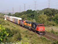 CN GP38-2W's 4776 and 4791 splice BNSF GP38-2 2090 on train #579, heading eastbound on the Halton Sub past Humber in the late morning sunlight. The short train is heading back to MacMillan Yard with five autoracks in tow after switching the Brampton Chrysler plant auto compound.
<br><br>
BNSF 2090 (originally built as BN 2090) is one of a bunch of 4-motor units from BNSF paying back horsepower hours to CN.
<br><br>
When it opened back in 1986 as the AMC Bramalea Assembly, the Brampton Chrysler plant did have a siding from the North Park Industrial Lead (aka BIT pullback track) into the plant for parts delivery, but due to noise complaint concerns from the nearby residential neighbourhoods it was never used (and parts and completed automobiles were moved by truck instead). That changed around 2013-2014 when auto loading facilities were built on site and sidings added.