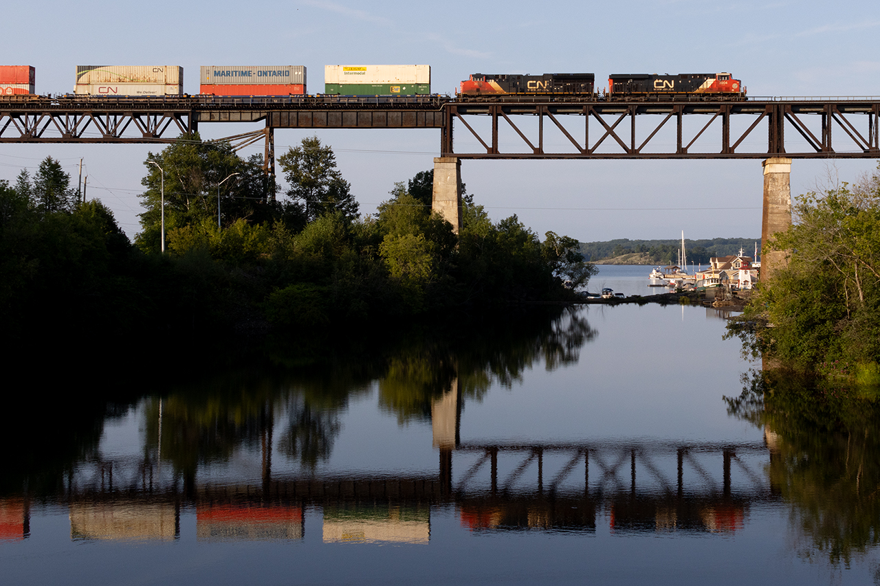 Just after sunrise, the first of 2 back to back stack trains creates a nice reflection in the Seguin River.