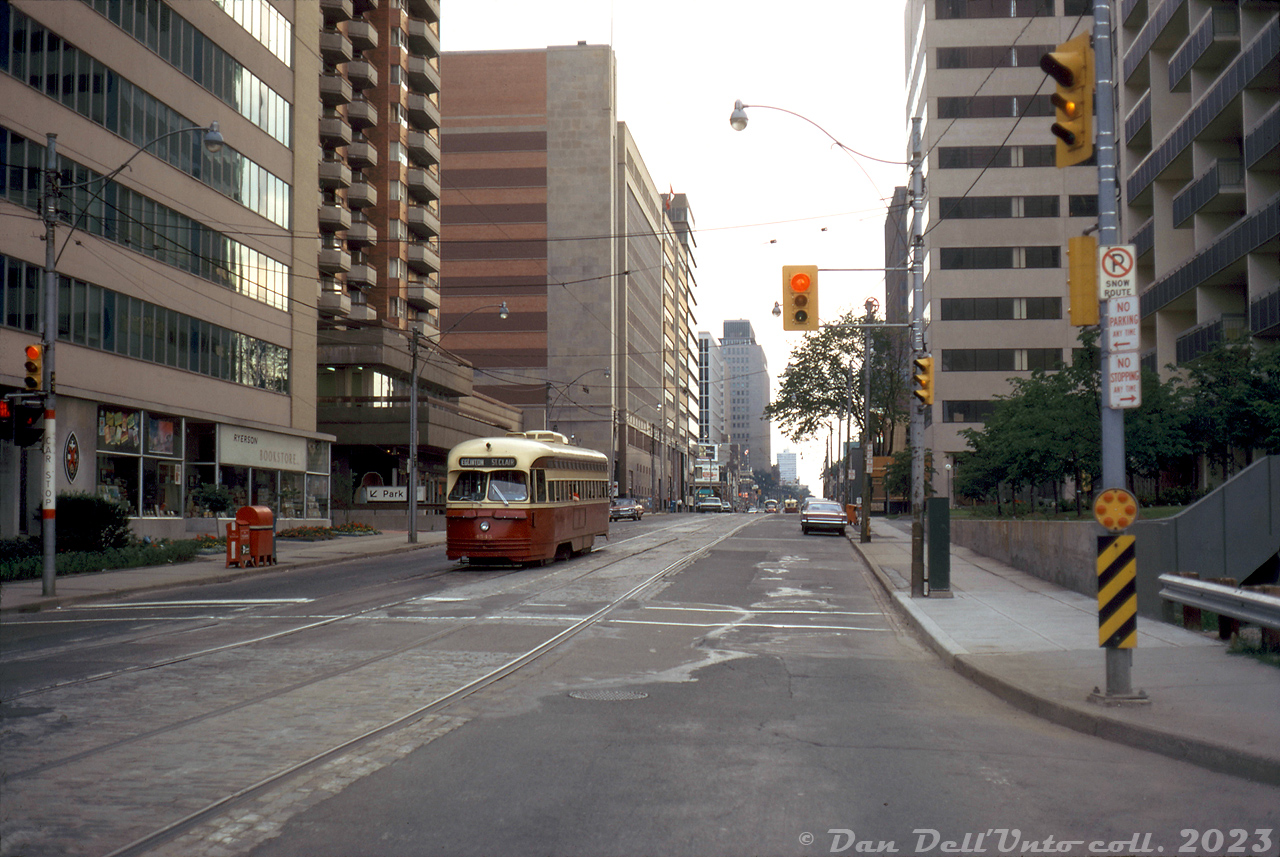 Bustling city streets? Maybe not mid-town Toronto in the 70's: TTC PCC 4545 is surrounded by a valley of apartment buildings and office towers as it heads eastbound on St. Clair Avenue East after departing the nearby St. Clair Subway Station streetcar loop (near Yonge). The PCC is paused at Avoca Avenue, making the short trip to over to Mount Pleasant Avenue in order to head north for Eglinton Loop. The "Ryerson Bookstore" signage on the building to the left is likely for the "Ryerson Press" publisher, rather than the polytechnical college/university of the same name. The quiet streets and sun angle suggest a weekend evening photo setting. 

In the interest of furthering density, today a lot of older, smaller office towers like these are being torn down across Toronto for even taller and higher density buildings built on the same parcels of land. 

Original photographer unknown (possibly a John Eagle photo), Dan Dell'Unto collection slide.