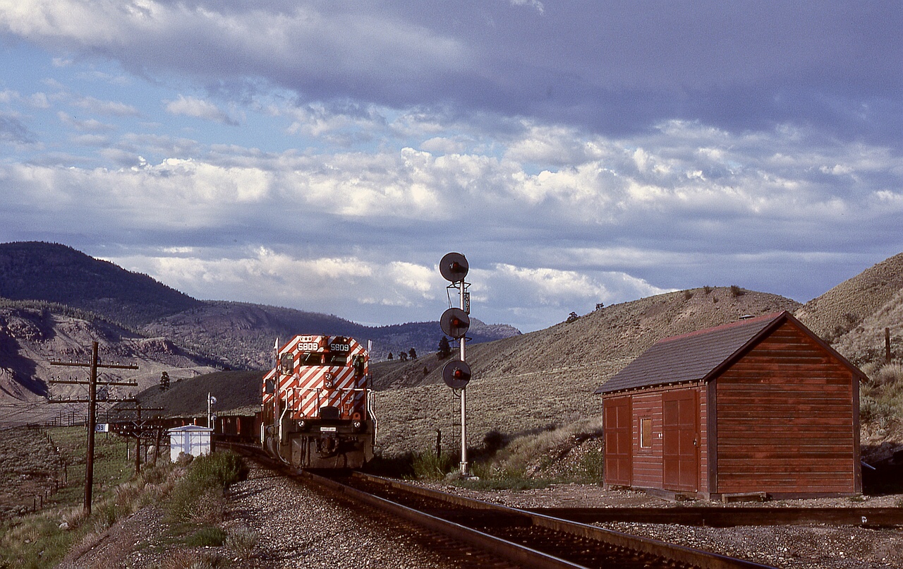 Access to Semlin between Walhachin and Ashcroft was by a rough Barnes Lake Road, but well worthwhile for the views possible.  Here, westbound coal loads symbol 803 with 5809 + 5800 on the headend plus mid-train remotes is lifting from the siding and passing milepost 39 after meeting an eastbound on Sunday 1980-06-08.