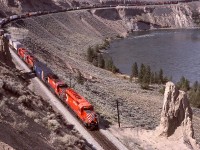 Between Ashcroft and Walhachin, and just a short distance west of the west siding switch at Semlin on Thursday 1987-05-21, an eastward train with CP 5855 + 5951 + robot car 1026 + two more SD40-2s is stretched out along the Thompson River as it passes long-standing glacial remnants at mileage 39.7.

<p>Semlin was named after area businessman Charles Semlin, and a good history of him is available at <https://apps.gov.bc.ca/pub/bcgnws/names/18848.html>.