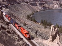 Between Ashcroft and Walhachin, and just a short distance west of the west siding switch at Semlin on Thursday 1987-05-21, an eastward train with CP 5855 + 5951 + robot car 1026 + two more SD40-2s is stretched out along the Thompson River as it passes long-standing glacial remnants at mileage 39.7.

<p>Semlin was named after area businessman Charles Semlin, and a good history of him is available at <https://apps.gov.bc.ca/pub/bcgnws/names/18848.html>.