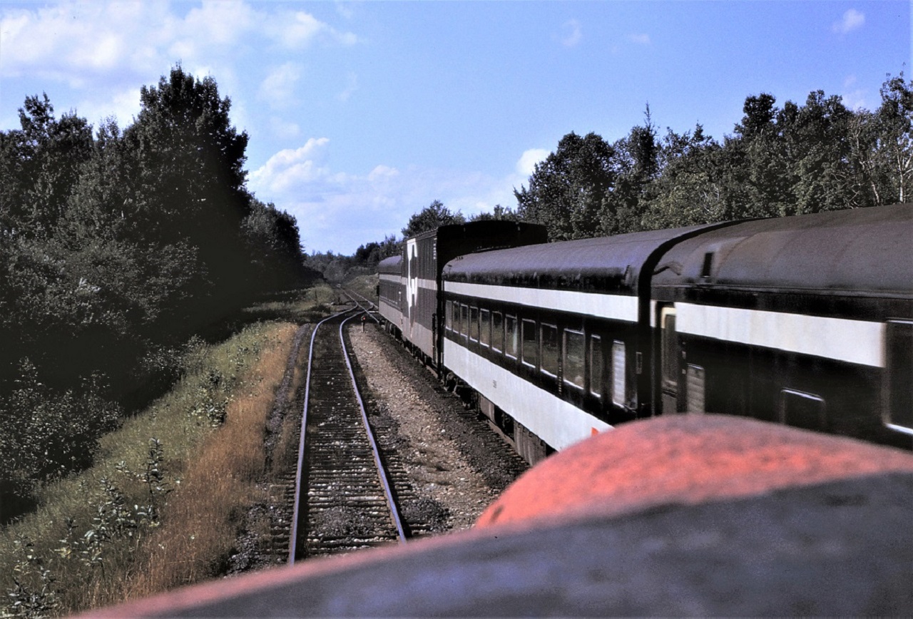 Viewed from the head end of # 3, the tail end of southbound # 4 has some interesting cars.  There appears to be a deadhead coach behind the sleepers, then comes the car-go-rail auto transporter, and finally a business car wearing the markers.  Number 3 is in the siding at the north switch of Woodward siding.  Location shown is approximate.