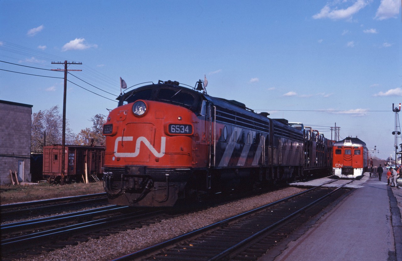 Here's an intriguing shot from the fall of 1969. An short freight led by two GMD passenger units heads west with one autorack and the van while express traffic is worked at the Burlington station. I can't read the full number, but that's a single 6400 series unit (I believe an RDC4).

Can anyone provide any additional information?