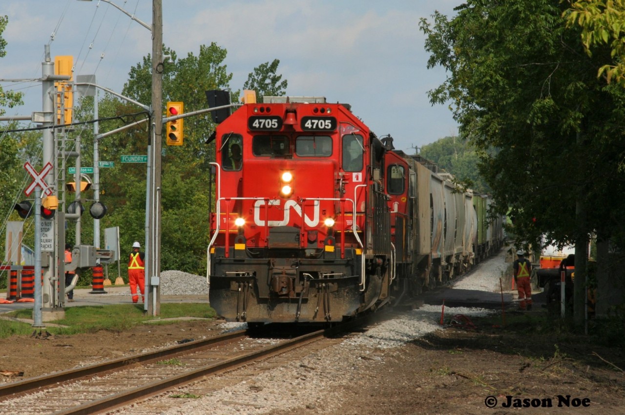 Last September CN performed upgrades to the main crossing in Baden, Ontario on the Guelph Subdivision. Foundry Street was closed for several days until the work was completed and the area around the crossing was heavily clear cut, which opened this view from the typically overgrown vegetation seen there during the summer months. Here, 4705 and 4131 slowly guide L568 over the newly surfaced crossing as foremen look on.