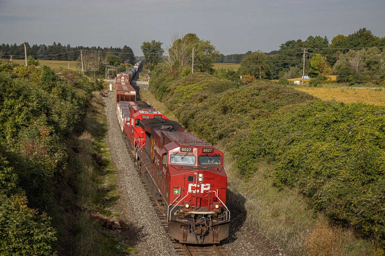 The sky behind the camera on September 17th was very patchy with clouds, and the sun was fading in and out.  I had been chasing this train from London all the way to Woodstock with the intention of catching it here at the bridge on the west end of the town.  Just as the train rolls by, the clouds part and the sun shines on the front of CP 8027 as it leads train 230 eastbound on the Galt Subdivision.  In the trailing position was SD30C-ECO number 5030, and mid-DPU was KCS ES44AC 4837.