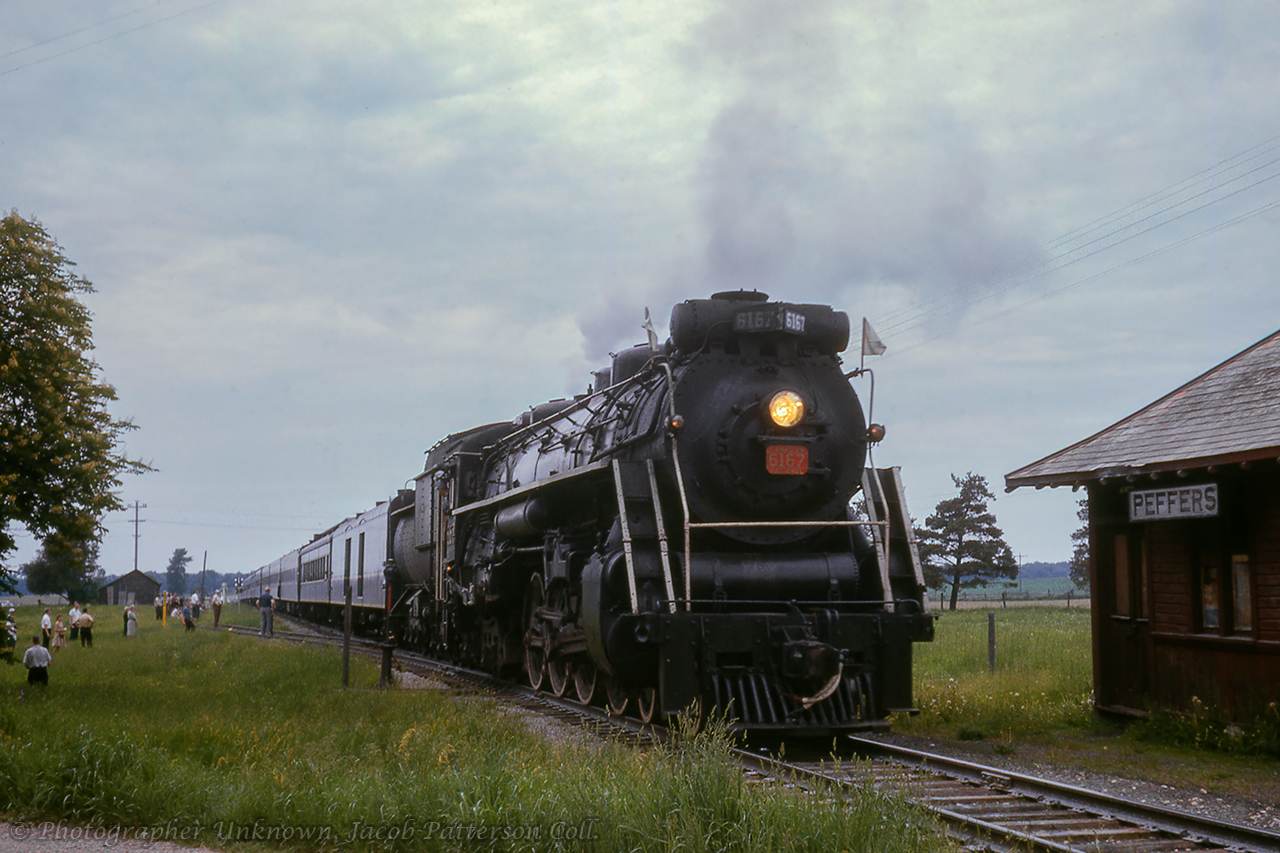 An Upper Canada Railway Society excursion behind CNR U-2-e 6167 is seen along the Newton sub at Peffers, where excursionists have detrained for a runpast at the old (second) station. The train, carrying over 500 passengers, travelled from Toronto - Dundas - Lynden - Guelph - Palmerston - Stratford - Kitchener - Georgetown - Toronto. 
 The eight car siding at left served the local stock pens and coal shed.Original Photographer Unknown, Jacob Patterson Collection Slide.