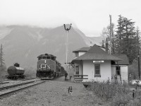 On CN’s westernmost subdivision, the Skeena between Terrace and Prince Rupert, the halfway point of Kwinitsa (mileage 48.2 from Terrace and 46.4 to Prince Rupert) was a vital communications point before CTC.  On weekdays, a regular Terrace Turn, running as No. 892 eastward from Prince Rupert, was operated to handle logs from Terrace to a pulp mill at Watson Island, and this photo shows the empties eastward behind CN 5589 + 5593 on Tuesday 1981-10-06 at 1159 PDT, with the depot operator providing a roll-by, and his dog ensuring a clear passage (and just missing my camera tripod as it zoomed past).<p>That Grand Trunk Pacific origin depot has been saved, now relocated to the waterfront in Prince Rupert as the Kwinitsa Railway Station Museum.
