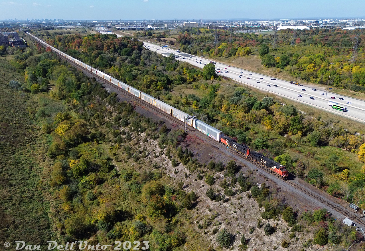 CN ES44AC 2877 and SD70M-2 8007 (with wonky cab numbers) race a GO bus on the adjacent Highway 407 as they roll train #276 eastbound downgrade through the equilateral turnouts at the west end of the Humber, about to cross the single-tracked Humber River bridge at Mile 4.3 of the Halton Subdivision.