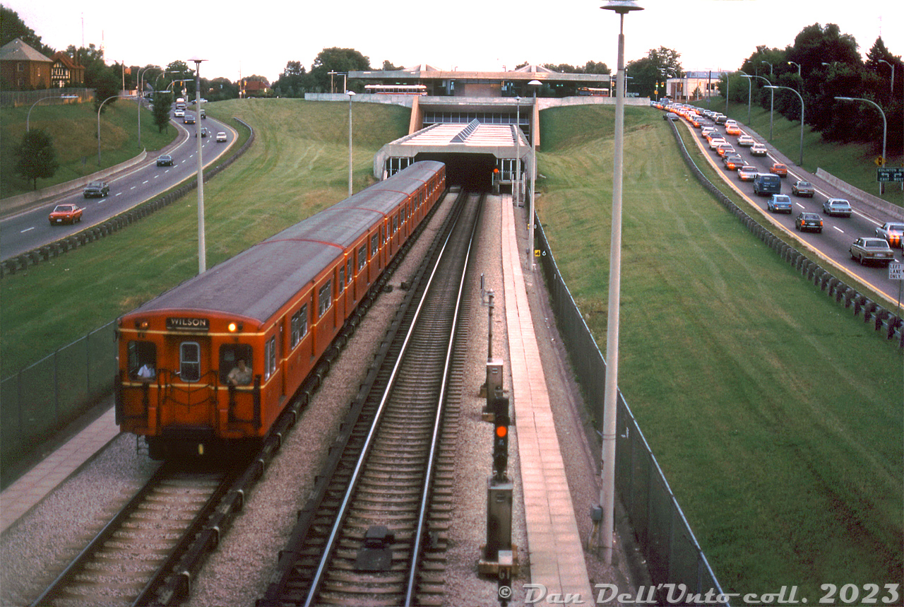 An evening view of the TTC's Eglinton West Subway Station, four years after it and the new Spadina subway line opened, shows a train of G-series "Red Rocket" Gloucester subway cars departing northbound for Wilson station (the then-end terminus of the line), as southbound traffic on the Allen Road backs up nearby. Eglinton West was where the Spadina line transitioned from running underground to open-cut, between the northbound and southbound lanes of Allen Road (what was planned as the Spadina Expressway running all the way downtown, but ended here at Eglinton Avenue due to pressure by citizens groups).

Some Flyer buses are visible at the station platforms above, including a TTC 83/8400-series D901 in the newer "CLRV paint", and an older D800 in the previous red and cream livery.

Original photographer unknown (possibly a John H. Eagle photo), Dan Dell'Unto collection slide.