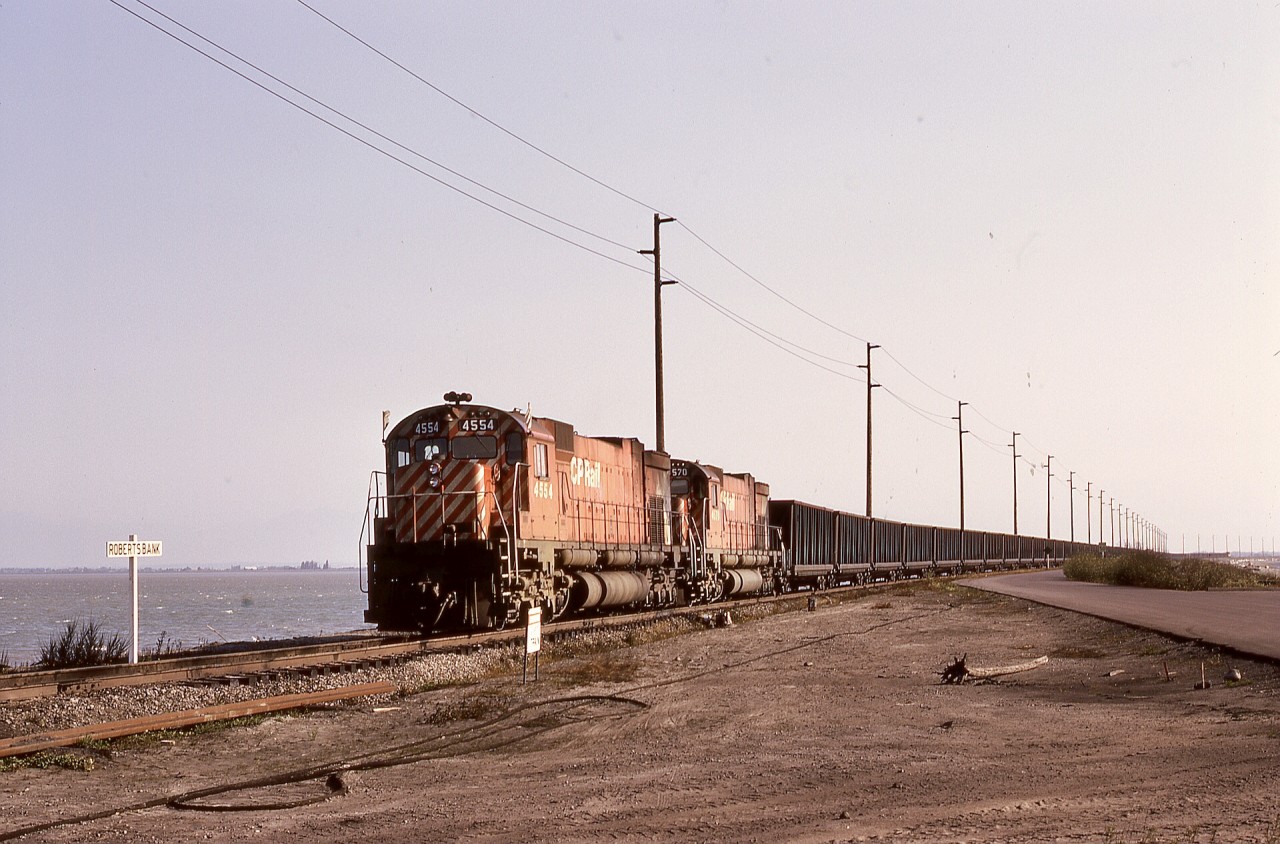 In the 50+ years since this scene, so much has changed.  The British Columbia Harbours Board Railway was only a few years since built (first CP coal train 1970-04-30), with only a single track along the causeway to the Westshore Terminals dumper loop at Roberts Bank, and MLW M-630 units like 4554 and 4570 (and unseen remotes) still reigned on the unit coal trains (an astonishing 88 cars long) from southeastern BC.  Now there is a significant yard on the left side of the photo, and a large intermodal terminal on the right behind the photographer, and the MLWs are long history.

Forty years (almost to the day!) later, this was where the last workday of my CP career occurred, as a roll-by inspection of a departing much longer coal empties with GE power.