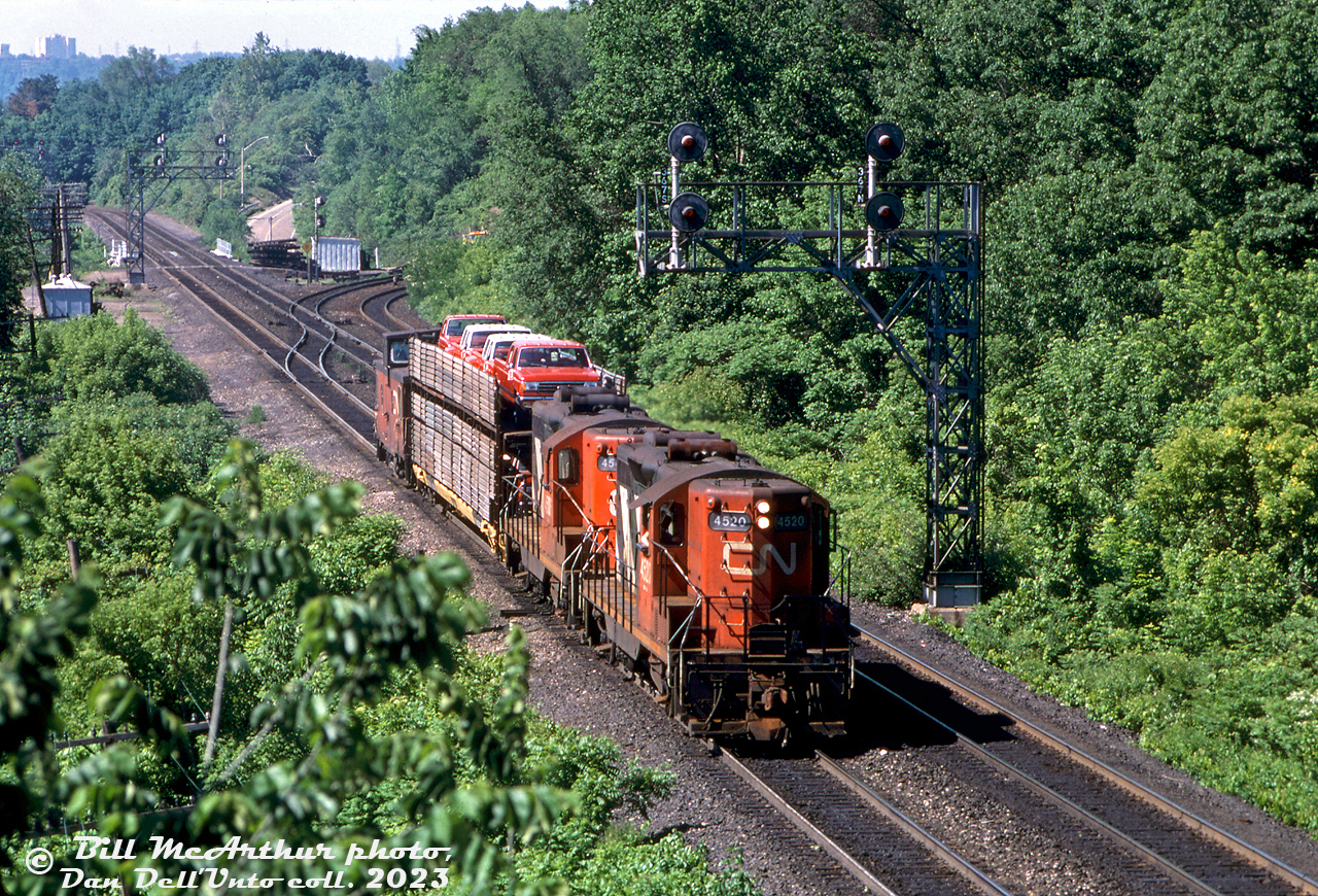 CN GP9's 4520 4506 roll through Bayview Junction with a short train #557, consisting of a caboose and lone bilevel autorack full of brand new Ford F-series pickup trucks. 

By the early 90's, CN's GP9RM rebuilt program had cut deep into the ranks of their old high-nosed GP9's, which were quickly becoming extinct as each year passed. 4506 would be rebuilt into 7081 in 1993, and 4520 into slug 278 in the same year.

Bill McArthur photo, Dan Dell'Unto collection slide.