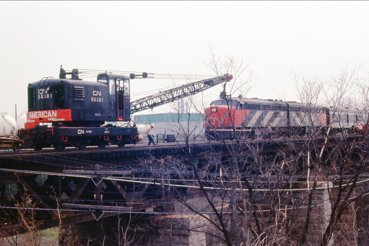 Here is another picture of the work gang on the Bronte creek CNR bridge laying down some rail with the help of CNR American self propelled crane as an eastbound CNR passenger rumbles by on the south track.