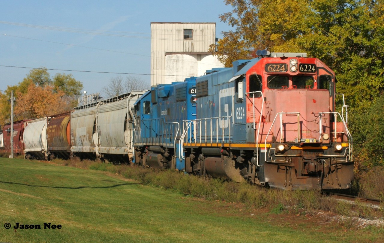CN L540 with GTW 6224 and CN 4910 are shoving across Queen Street on the Huron Park Spur in Kitchener, Ontario as they return from lifting cars at the CP interchange. 

One year later and as of this October crews were in the process of removing the former Kissner Milling silos seen in the background.