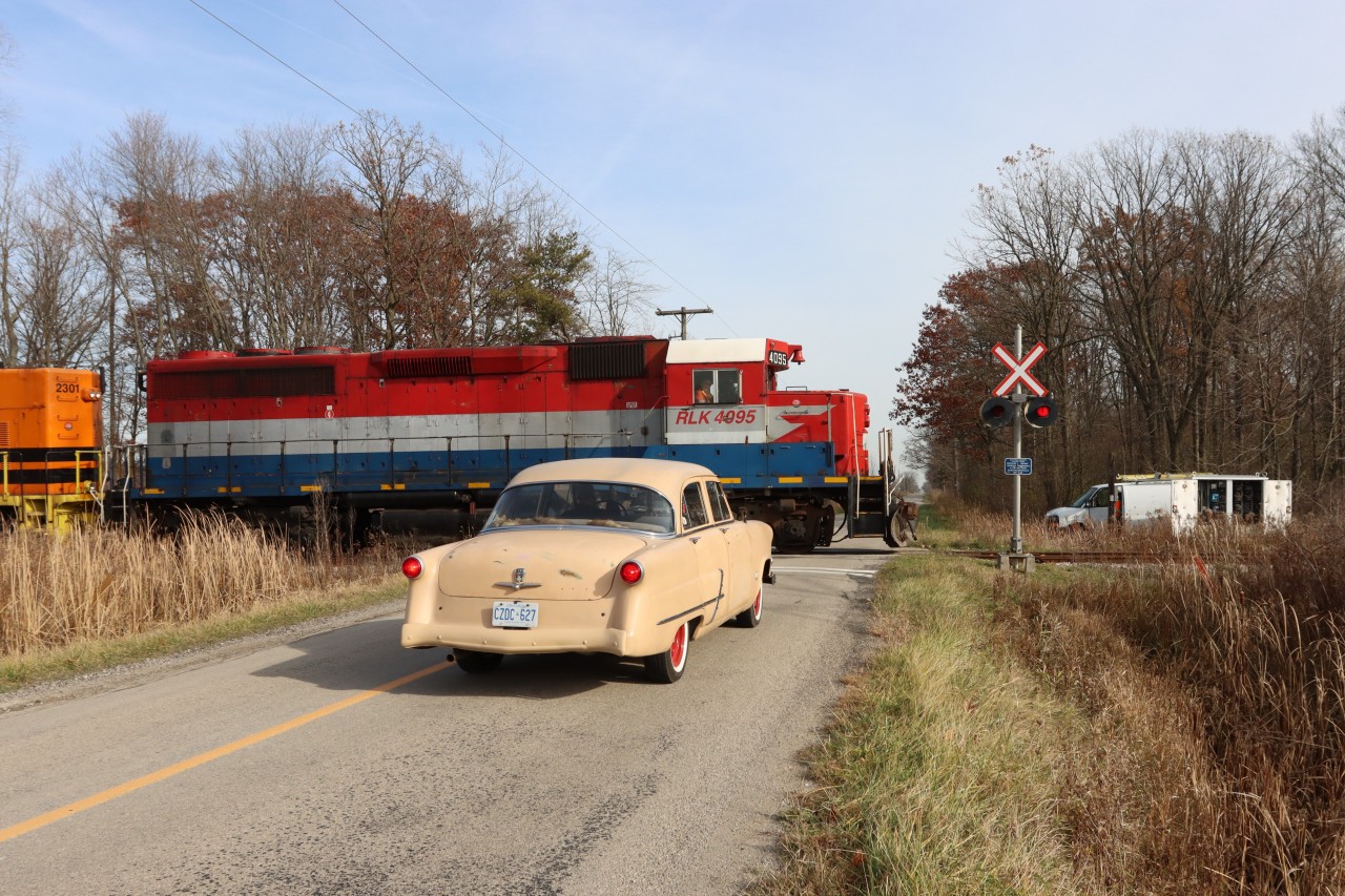 The driver of the 1953 Ford Customline waits patiently as RLK 4095 (SOR 591) occupies the crossing on Concession 4, Walpole, southbound to Nanticoke. The X Rail Signal Maintainer is busy on site doing scheduled tests and inspections.
