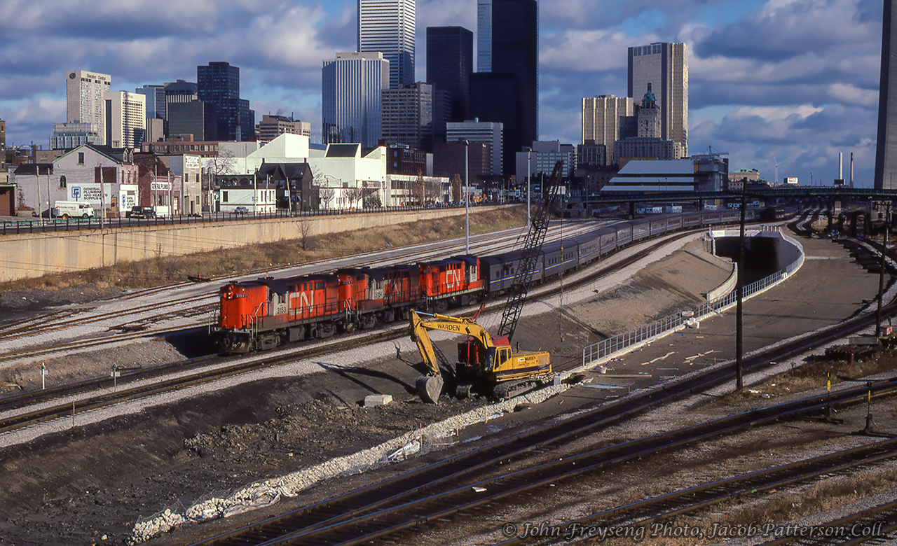 Tempo-equipped VIA 75 departs Toronto for Windsor behind three of CN's RS18m locomotives.  Like the skyline, the railway scene is changing with the construction of the fly under and associated track realignment.  Note the VIA markings on the Tempo coaches, while the units retain their CN markings.  These units were still owned by CN and leased by VIA until their retirement in 1983.John Freyseng Photo, Jacob Patterson Collection Slide.