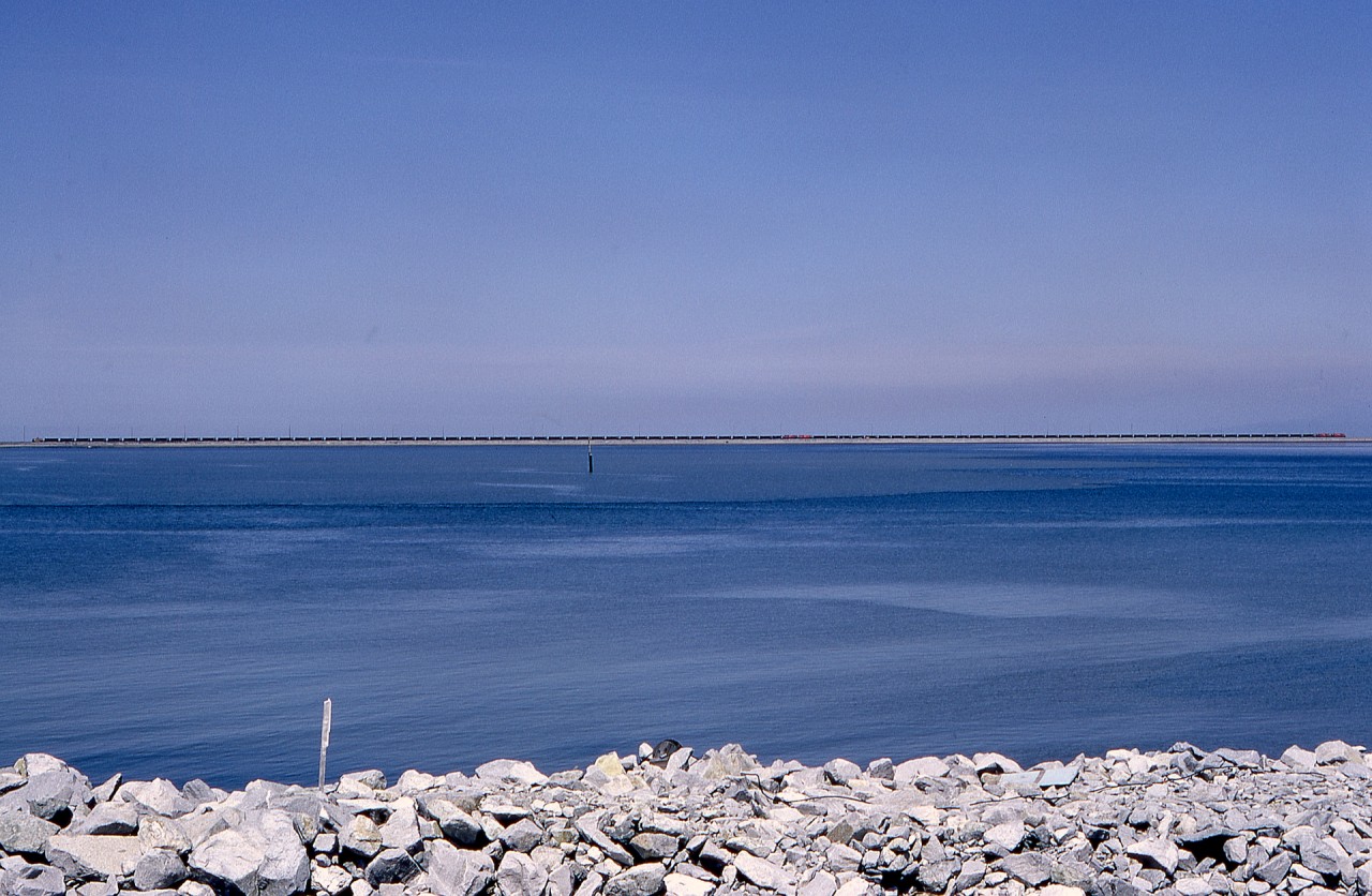 Perhaps one of the most boring railway photos I have taken, this is a view from the BC Ferries road causeway at Tsawwassen northwestward to the rail-and-road causeway to the Westshore Terminals export coal terminal at Roberts Bank, and is notable for being in the early years (1972-05-30, so 25 months to the day) of operation there, and for showing an entire CP coal train with two MLW M-630s leading, then 39 cars plus two units with a robot car, then 49 more cars and a caboose, all stretched out on the single track after exiting the dumper loop.  Amazing for the time, 88 cars in one train!  This is from the second roll of Kodachrome in my two-weeks-old Pentax Spotmatic camera, another amazing advance at that time.

In those early years, the entire causeway was off limits to railfans and the general public, with a gatehouse at the east (shore) end, so the specific equipment identity is unknown.