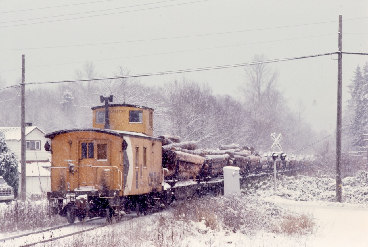 As a literal followup to my post a week ago of a Nitinat log train in the snow, here is the tailend, nicely punctuated by caboose CP 437148, right on the crossing of Westholme Road in the village of the same name on Tuesday 1980-01-08 at 1324 PST.  Those logs are from Lake Cowichan, and are for dumping into the saltchuck at Crown Zellerbach’s dump at Ladysmith, 11 miles ahead, then it will be cab hop onward to Wellcox yard on the Nanaimo waterfront.

By the blind luck of my timing on the planet, I got to know train order and caboose operations well on Vancouver Island, and frequently photographed the tailend of a train after catching the headend.  Years later, in 1989, part of my work was readying locomotive equipment for cabooseless operation, distance-counting digital speedometers and end-of-train communications devices, and I was really glad I took so many caboose photos.

A very Happy 2024 to all.