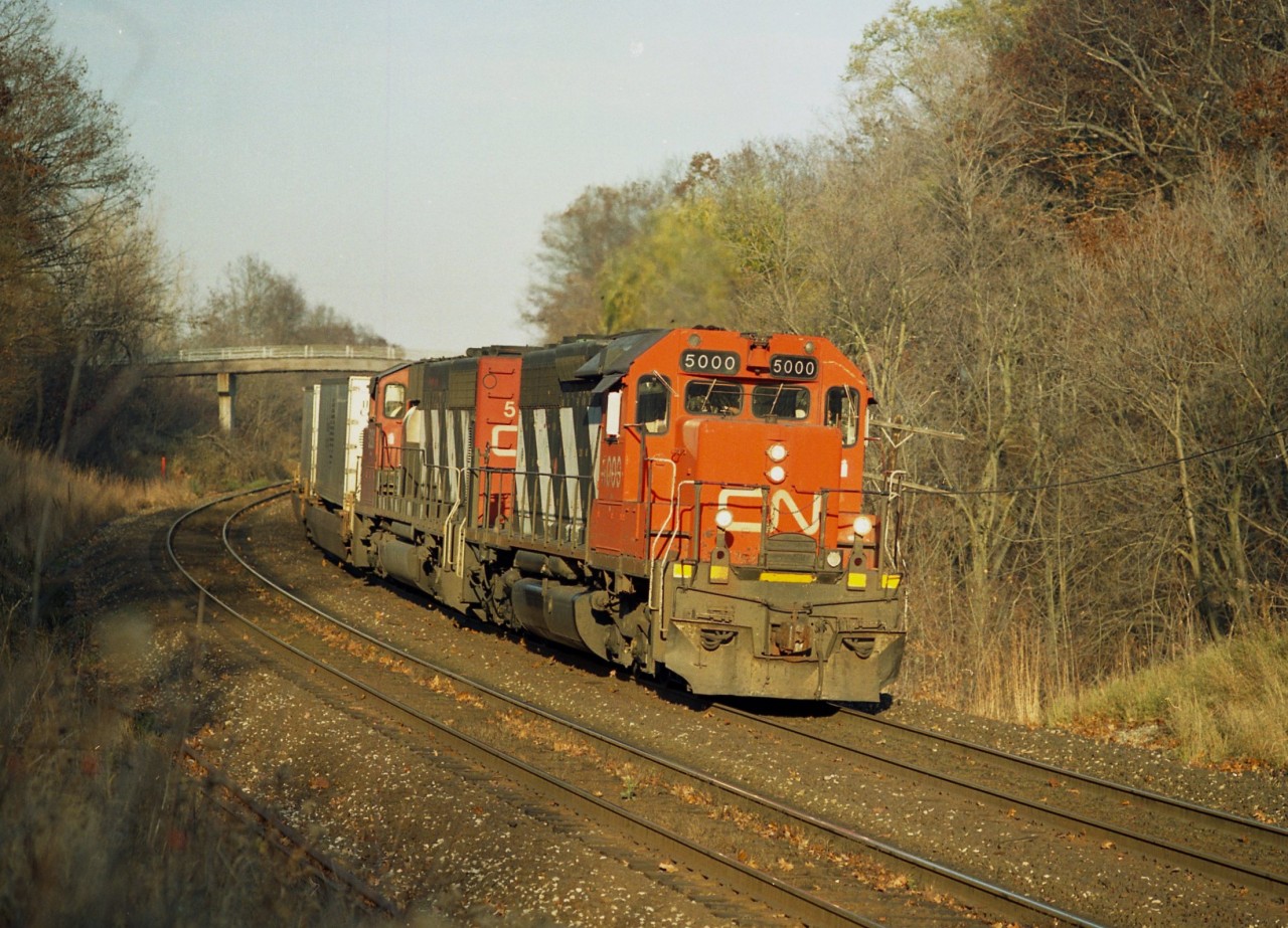 The Head of the Class !!  First of an illustrious series of SD40 locomotives on this railroad, CN 5000 leads a westbound on approach to Bayview Jct in the late afternoon sun of a mild November day.  This unit was built in September of 1967 and held on almost to the bitter end.  There are none left on the once 241 strong on the CN roster and this unit was one of the last dozen to be retired.  Don't really know, but I assume it was scrapped.
Seeing this was a surprise, as I thought it was based out West. Second unit is 5281.