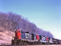 Three Geeps(4520-4586-4575) chanting along westward on the Dundas hill, a nice sunny spring day. Not exactly sure of the mileage, perhaps mile 3 point 5,and east of the Sydenham Road overpass. Kodak Instamatic Memories from long ago.