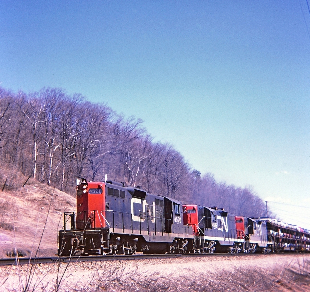 Three Geeps(4520-4586-4575) chanting along westward on the Dundas hill, a nice sunny spring day. Not exactly sure of the mileage, perhaps mile 3 point 5,and east of the Sydenham Road overpass. Kodak Instamatic Memories from long ago.