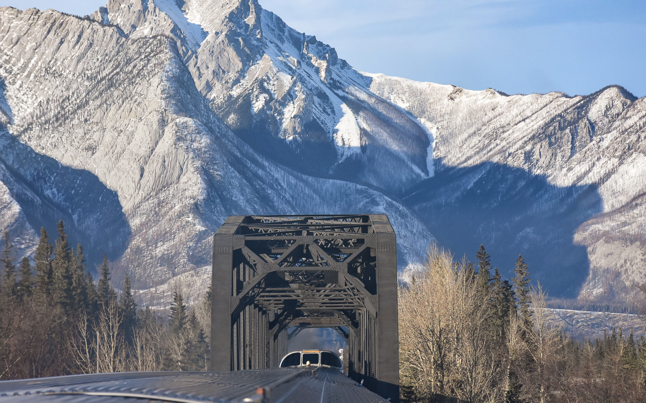 Rock & Steel  
Two very imposing sights at CN Henry House, AB Mile 225.8 CN Edson Sub. 
The Rocky Mountains, and the CN trestle over the Snaring River where it joins the Athabasca River east of Jasper, AB. 
It was a beautiful afternoon to have the whole dome of VIA 8504 Skyline all to myself. Easy to move around front to back and side to side when it's wide open. :-) 
Thanks to my friend R.W. for editing the photo.