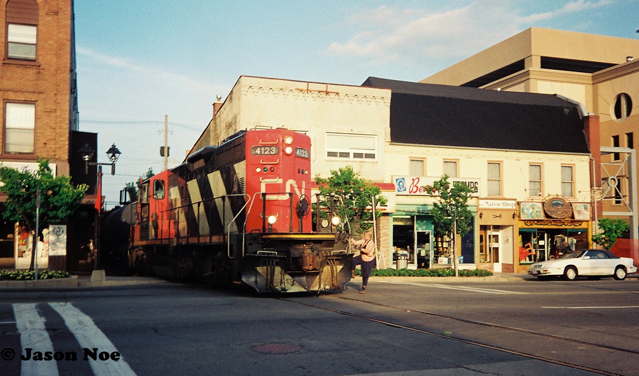 On the evening of August 18, 1993, the CN 15:30 Kitchener Job with GP9RM 4123 is viewed crossing King Street in downtown Waterloo, Ontario as it hauls two tank cars to Elmira on the Waterloo Spur. 

A follow-up photo on the same evening can be seen here.

http://www.railpictures.ca/?attachment_id=35441
