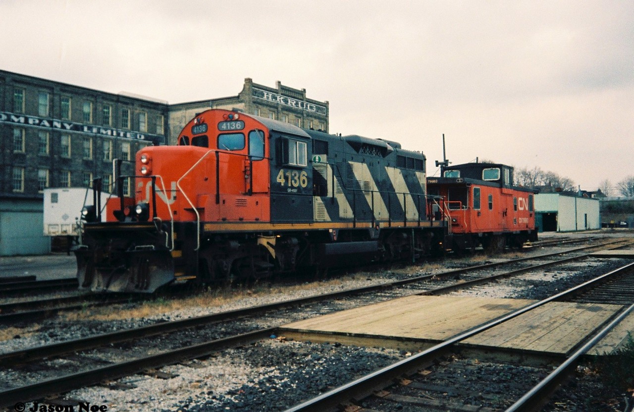 During a weekday afternoon, CN GP9RM 4136 and caboose 79883 are viewed parked awaiting their next job in front of the Kitchener, Ontario station.