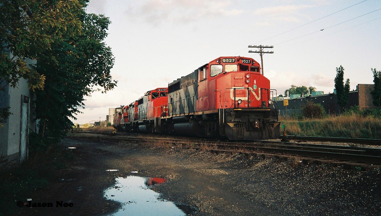 CN train 421 is viewed at the Kitchener yard with 9527, 9622 and 4128 along with caboose 79436. The train had arrived light power in Kitchener from Guelph and proceeded to lift the caboose at the Kitchener yard as well as the loaded cars with recently built Budd automobile frames seen in the background. Once all their work was completed, 421 would eventually depart towards London with 79436 in its rightful spot on the tail-end.