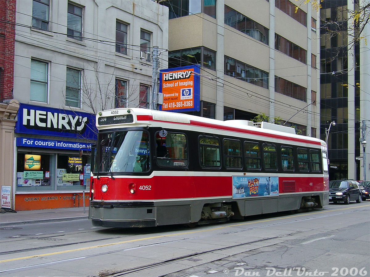 TTC CLRV 4052 waits eastbound on Queen Street at Church Street on a 504 King run (that's diverted onto Queen in order to short-turn at Church), as its operator manually switches the track with a large switch bar (out of frame) in order to divert the car down Church and back on-route at King Street to complete its late morning short turn.
In the background is one of camera and electronic chain Henry's Cameras stores: their Toronto Outlet Centre on Queen west of Church, a stone's throw from their main Toronto flagshop store on Queen east of Church. Many older rail photographers likely frequented both shops over the years to get the latest and greatest, or a deal or two on something older. From a few visits at the time, the outlet store sold mainly used items including no shortage of old film cameras and film-mount lenses.

The outlet store was closed sometime between 2009-2011 (operations continued at the flagship store nearby), and TTC 4052 was retired in September 2019.