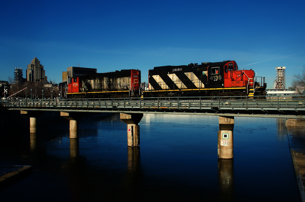 The crossing gates are starting to go up at left as CN 500 leaves the Port of Montreal light power after bringing in baretables.