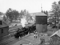 The joint excursion of the Upper Canada Railway Society and Canadian Railroad Historical Association behind E-10-a 2-6-0 90 and N-4-a 2-8-0 2649 is seen pausing briefly at Bancroft before continuing north to wye at York River.  The train had stopped to allow local children to board the train for a ride up to the wye and back, after which the locomotives <a href=https://www.railpictures.ca/?attachment_id=50907>would take on coal</a> and water. <br><br>Departing Belleville amid the light rain that morning at 0645h - with a crew from the National Film Board setup in the baggage car - the excursion ran along the Campbellford Subdivision to Anson Junction, taking the east leg of the wye onto the Maynooth Subdivision. Seen here, the train would pause briefly at Bancroft before proceeding three miles north to York River where the train could be wyed for the return trip. Arriving back at Anson Junction, the excursion would continue south into Trenton, turning on the wye before returning north to Trenton Junction to rejoin the Oshawa Sub mainline for the short twelve mile run back to Belleville. The special reached a top speed of 55mph on the high iron, running barely 30 minutes ahead of Toronto - Montreal train 6, due into Belleville at 1815h.<br><br>Notes of the trip per John Freyseng's extensive article in the June 1959 UCRS newsletter. Neither of these locomotives would last another year, with 90 meeting the torch in February 1960, and 2649 that March.<br><br><i>Basil Headford Photo, Jacob Patterson Collection.</i>