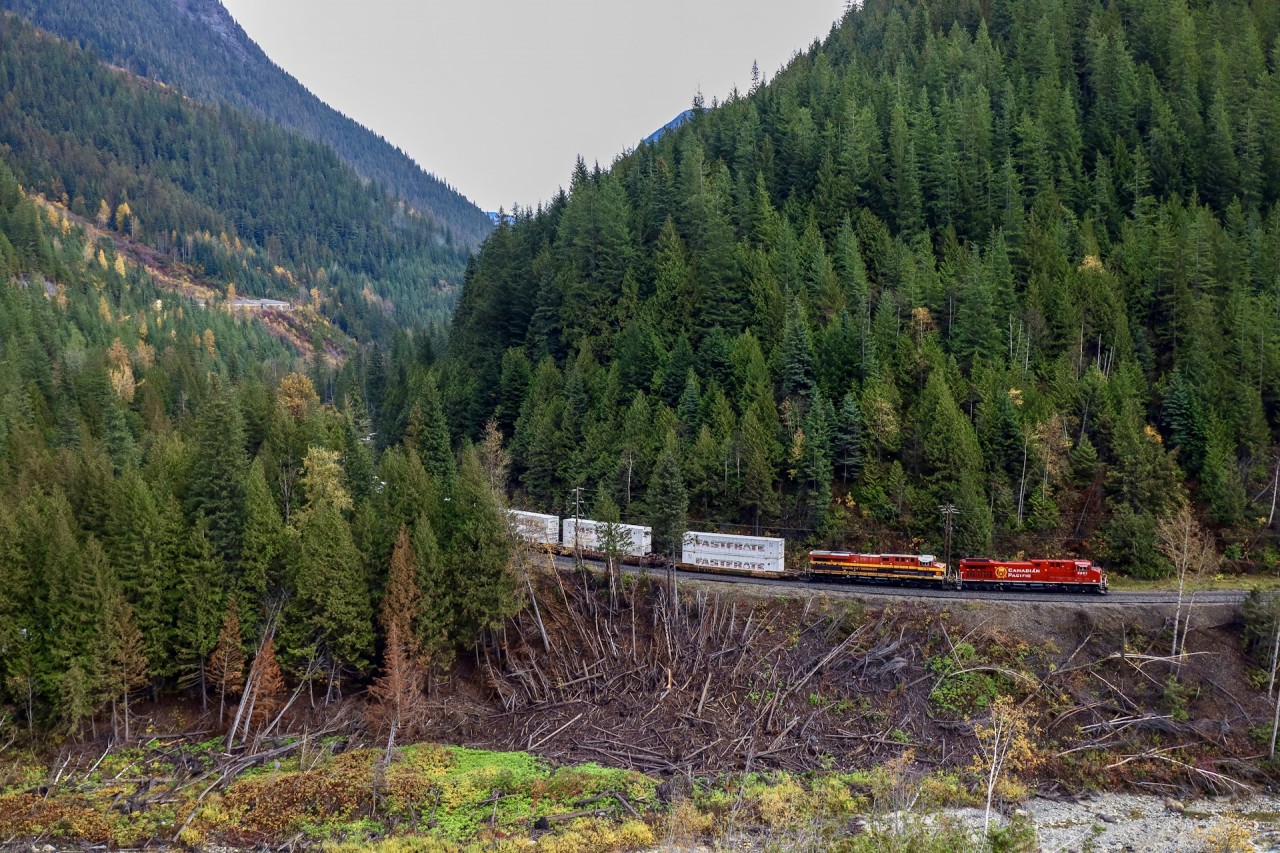 After conquering Rogers Pass, the terrains does not get any easier for CPKC 101 as they follow the Illecillewaet River towards Revelstoke. Shot beside one of the many snow sheds on Highway 1, the damaged trees along the right of way show just how powerful an avalanche can be.