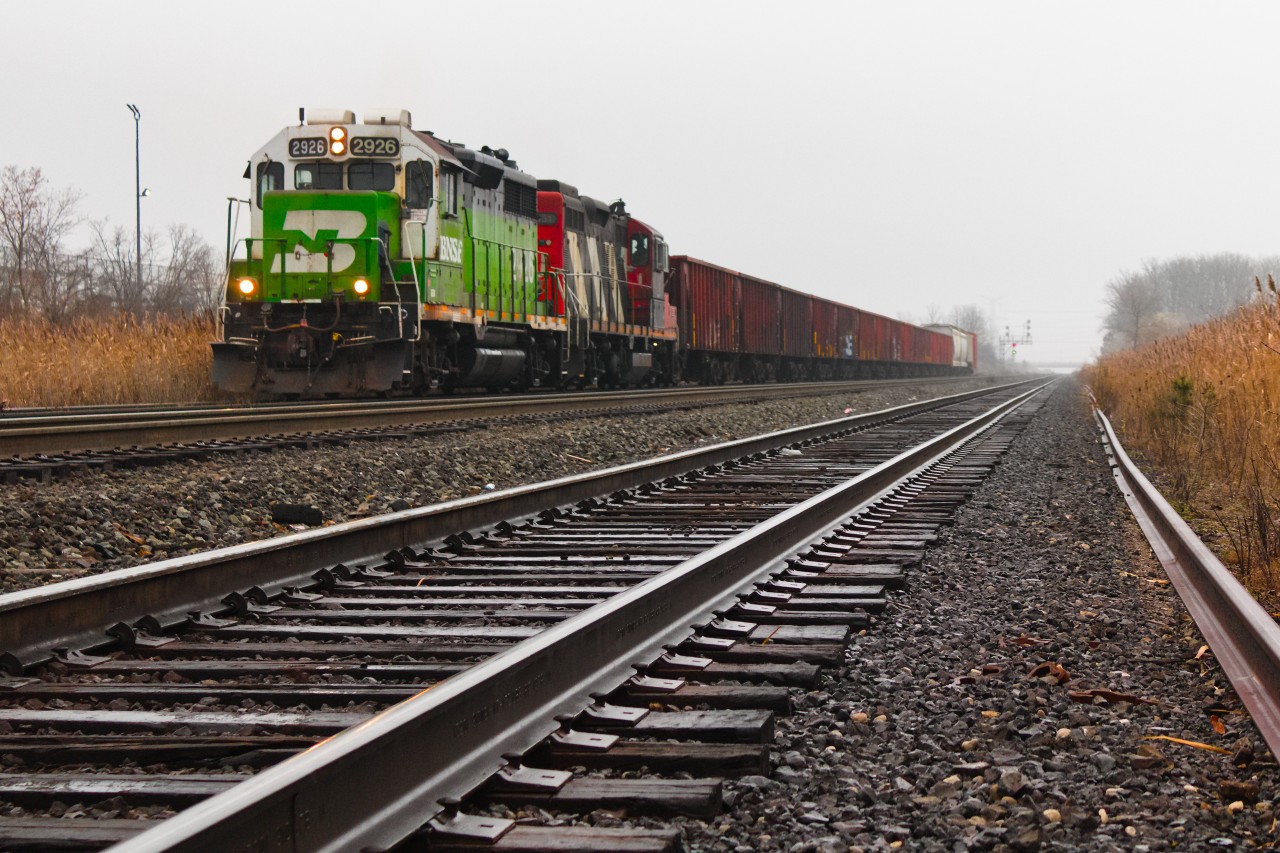 It seems like BNSF's unorthodox method of paying off horsepower hours to CN continues to pay dividends to railfans with the case of this consist on L55931 08:
- "BN Whiteface" painted GP39E to boot
- "CN Zebra" painted GP9RM second
- Followed by 14 loads of ballast in a continuous cut of early-CN open-top hoppers bound for a set-off in Torbram.
Such an occurrence would've been unimaginable at the start of the year, yet became a reality thanks to the close timing of both units for 90-day inspections from London (4131 back on 12/01 from 583) and Belleville (2926 back on 11/23 from 518) coupled with the order for ballast to leave Toronto, and the actions of power planners to conjure up this lash-up. It began from scratch with 4131/4726 running 529 on the 4th, evolving to 4131/4726/2926 on the 7th after 529 lifted 2926, only to immediately drop the 4726 the night before this 559. Ironically, 4726 was meant to replace 2926 over in Belleville and had already returned to Toronto on the 3rd. The eagerness by power planners to run it for only short periods at a time implies perhaps that it was underperforming or was undesirable by crews. Either way, this also contributed to the creation of this 559 whose local status was retained by the 4 revenue cars on the tail end and the awaiting industry empties in Brampton. The spot was rather rushed as a result of hearing "BNSF 2926 West" call their departure from Mac Yard before even getting trackside, hence, any shot would've beat no shot at all. The consist of 559 would come as a surprise after the fact, and I enjoyed the sight as it cleared Snider West.