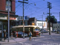 70's street scenes: a TTC PCC streetcar (that appears to be 4353) is stopped at the lights as passengers get on and off, as viewed from the adjacent street corner. Pedestrians cross the street in front, and a mother and child wait to head into the corner confectionary store (Drink Coca-Cola!). On the other side of the street, cars wait to fuel up at the nearby Shell gas station. High rise buildings along the busy University Avenue thoroughfare can be seen poking up in the distance amid all the aerial TV antennas in the sky, including the new Simpsons Tower at Bay and Queen.
<br><br>
The corner store at Dundas and McCaul (photographed years earlier <a href=http://www.railpictures.ca/?attachment_id=40753><b>here</b></a>), last home to a cafe, was demolished in 2021 when the block was cleared out for a new condo development (the Shell gas station site had been redeveloped many years earlier.
<br><br>
<i>Original photographer unknown, Dan Dell'Unto collection slide.</i>