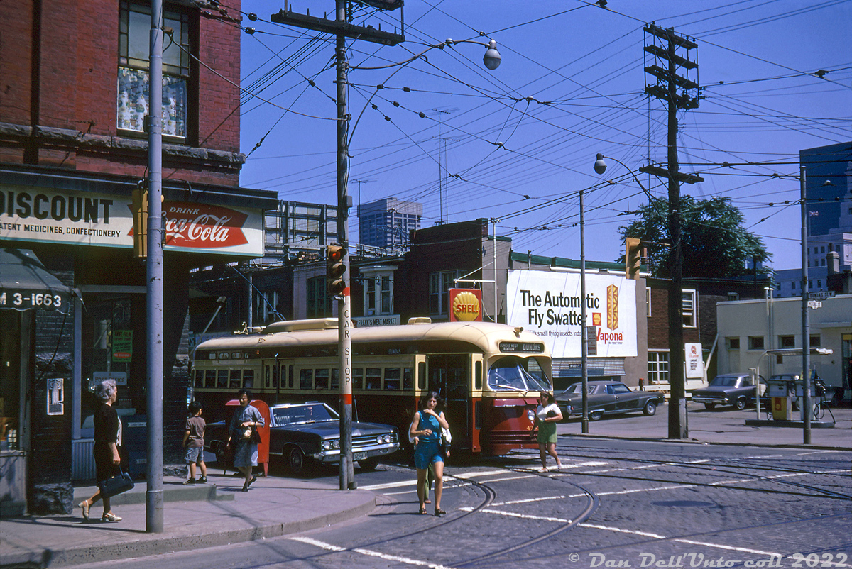 70's street scenes: a TTC PCC streetcar (that appears to be 4353) is stopped at the lights as passengers get on and off, as viewed from the adjacent street corner. Pedestrians cross the street in front, and a mother and child wait to head into the corner confectionary store (Drink Coca-Cola!). On the other side of the street, cars wait to fuel up at the nearby Shell gas station. High rise buildings along the busy University Avenue thoroughfare can be seen poking up in the distance amid all the aerial TV antennas in the sky, including the new Simpsons Tower at Bay and Queen.

The corner store at Dundas and McCaul (photographed years earlier here), last home to a cafe, was demolished in 2021 when the block was cleared out for a new condo development (the Shell gas station site had been redeveloped many years earlier.

Original photographer unknown, Dan Dell'Unto collection slide.