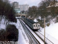 A 4-pack of subway cars with two of TTC's Montreal-build MLW M1's (5300-5335 series, the only MLW order) trail two Hawker Siddeley H-series cars on a northbound Yonge line train in this wintery scene. The consist is passing through the open-cut section of the Yonge Line north of Rosedale Subway Station, passing under Roxborough Street, and about to duck back underground for their stop at Summerhill Subway Station. The green low-rise office building in the background, off Price Street, survived until the early 2020's before behind demolished for redevelopment.
<br><br>
<i>Robert D. McMann photo, Dan Dell'Unto collection slide.</i>