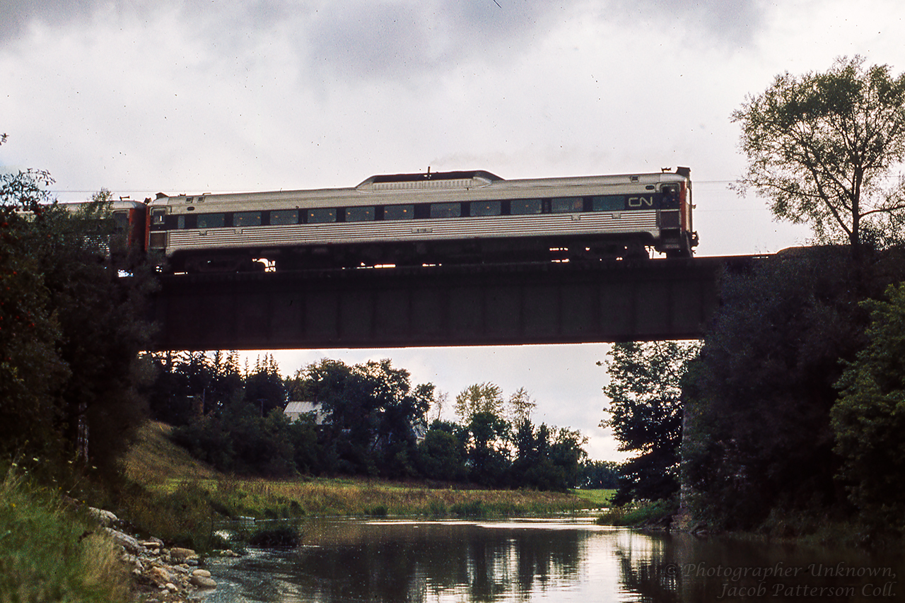 CN 6116 is seen shoving the consist of three RDCs (6120, 6003, 6116) westbound in preparation for a runpast on the Goderich Sub, crossing the Thames River at Mitchell.  The trip ran from Toronto - London via the Oakville and Dundas subdivisions to reach the GMD plant for a tour. Following the tour, the trip departed London for Hyde Park, taking the Exeter Sub north to Clinton and on to Goderich. Returning to Stratford, via the Drumbo sub to Paris, and back to Toronto.  Bruce Acheson captured the train later in the evening during a runpast on the Drumbo Sub.Original Photographer Unknown, Jacob Patterson Collection Slide.