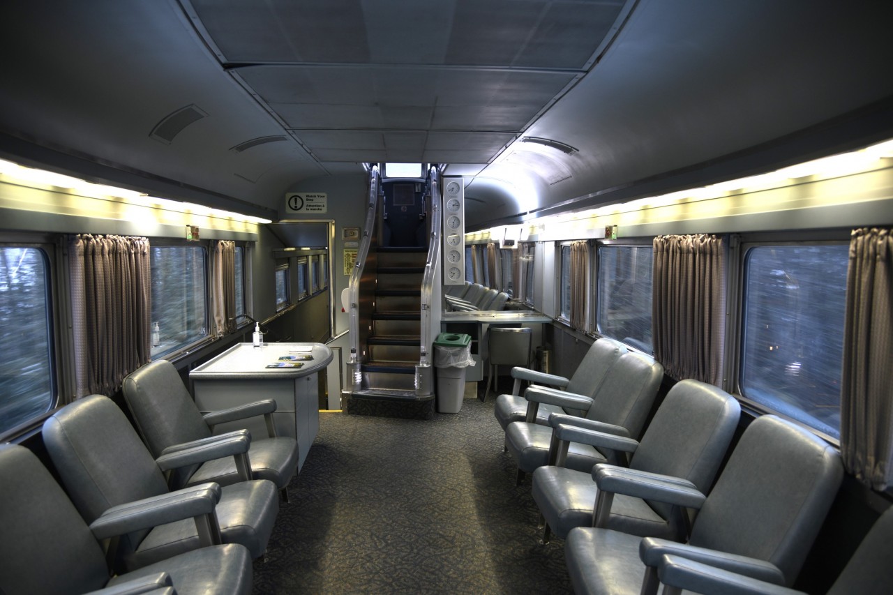 The opposite view  
Further to my trip last month, and posting showing the dated furnishings in VIA 8707 Kokanee Park on VIA 005 The Skeena, here is a view in the same car looking towards the staircase to the dome level. 
As in the original CP Canadian Park cars, there are six clocks for Canada's time zones (none of them accurate), a stationary desk for writing a post card, and the hallway leading to the Mural Lounge. 
What a great car to travel in! :-)