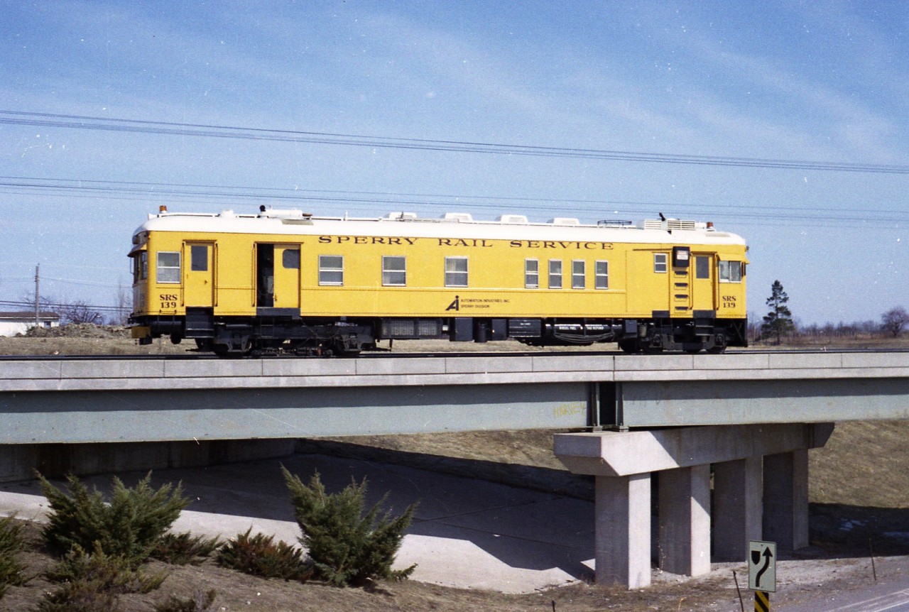 I have to admit I do miss those colourful Sperry cars that used to roam the rail system. I don't know how long it has been since the cars were replaced by rather unappealing trucks, but it has got to be 25 years. What a difference.  With the cars there was room to roam around; with the truck you are pretty much stuck in the seat. Usually when I see one of the Sperry Rail Service trucks these days it is parked alongside the line at a crossing waiting for rail traffic to clear. Must make for a long day for those fellers.
This image was taken in early March of 1978 showing the SRS car #139 crossing over Fourth St Louth in West St. Catharines.