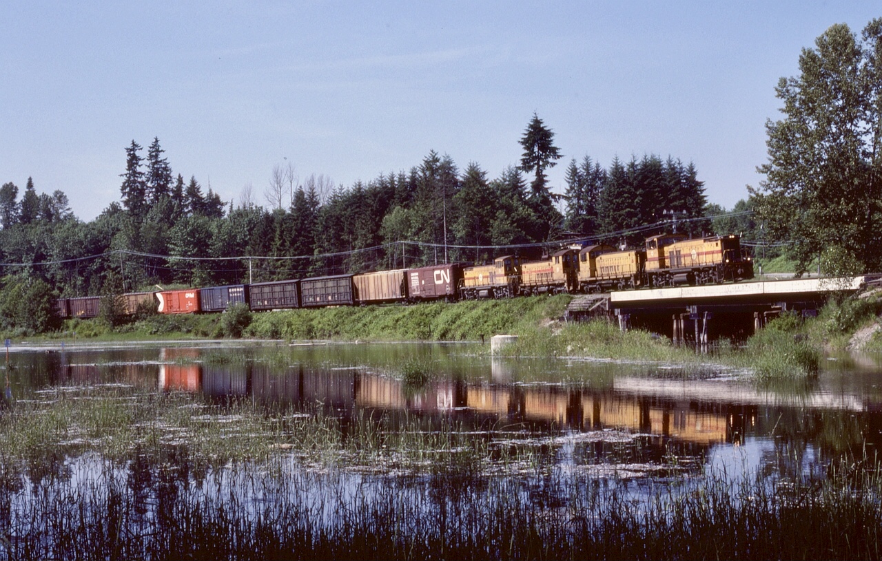 On 1982-05-29, a major fire on the swing span of the Fraser River Railway Bridge between New Westminster and Surrey brought the multi-user rail traffic to a halt for a long time.  BC Hydro’s Valley Freight from New Westminster to Huntingdon utilized a detour route over CP’s New Westminster, Cascade and Mission subdivisions to gain access to their own track at Abbotsford, and due to restrictions on one small portion near New Westminster, were required to use four-axle power on detours.  Thus, an eastward detour leaving Haney on Wednesday 1982-06-09 had BCH 152 (MP15DC) + 906 + 908 (SW900s) + 153 (MP15DC) as they crossed Kanaka Creek on CP rails at 1559 PDT.

BN and CN ran over the same detour route, a bonanza for railway photographers and Kodak.  Having relocated from Vancouver Island to Port Coquitlam just a few months earlier, I was delighted with the many opportunities.