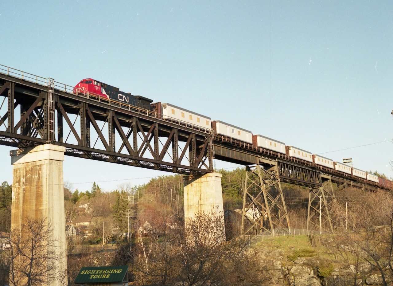 Crossing the majestic Parry Sound CP bridge, a CN work extra with a long train of Camp Cars behind CN 2585 takes advantage of the directional running in which CP and CN trains run north (read: west) and southward trains use the CN line thru town.  Sun is perfect on this structure in the late afternoon.