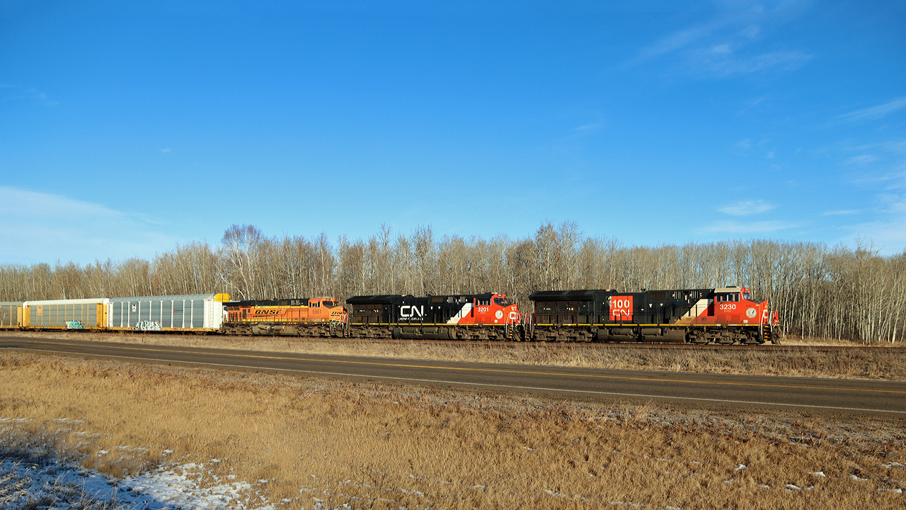 CN 3230 heads east past North Cooking Lake hauling auto racks and empty sand hoppers.