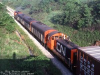 Seeing one B-unit was common, two B-units was a frequent occurrence, but today, CN #436 has cornered the market on B-units: three CN F7Bu's (9190, 9192, 9195) make up most of #436's power today, with GP40-2W 9656 in the lead and SW1200 7021 trailing (not being equipped with MU, it was just along for the ride). The train is on the Grimsby Sub in St. Catharines, possibly viewed from the St. Paul Street overpass.<br><br>As part of it's 1970's rebuilt program, CN rebuilt 10 F7B units into the 9190-9199 series to run with their 30 rebuilt F7A's. They were common power running with the A's, GP9's, and more modern power into the late 1980's. Most ended up scrapped, but CN 9190 was acquired by the Feather River Rail Society and painted up as Western Pacific 725C, to go with their WP FP7 805A.<br><br><i>Reg Button photo, Dan Dell'Unto collection slide.</i>