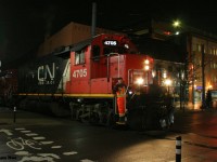 CN L566 with 4705 and 7025 slowly eases across King Street in downtown Waterloo, Ontario as they head to Elmira on the Waterloo Spur. 