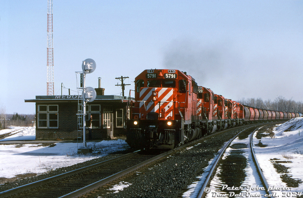 There's no shortage of power on this southbound: CP SD40-2's 5791, 5720, SD40 5526, 5661 and another unknown '40 lead train #300 past the station at Medonte, as the operator gives a wave to the head end crew. The track to the left is the old CP Port McNicoll Sub, that lead to Port McNicoll and Midland via some running rights over CN's Midland Sub. Traffic up front is a sold grain train consist of Canada, Saskatchewan and Alberta government cylindrical covered hoppers.

Peter Jobe photo, Dan Dell'Unto collection slide.